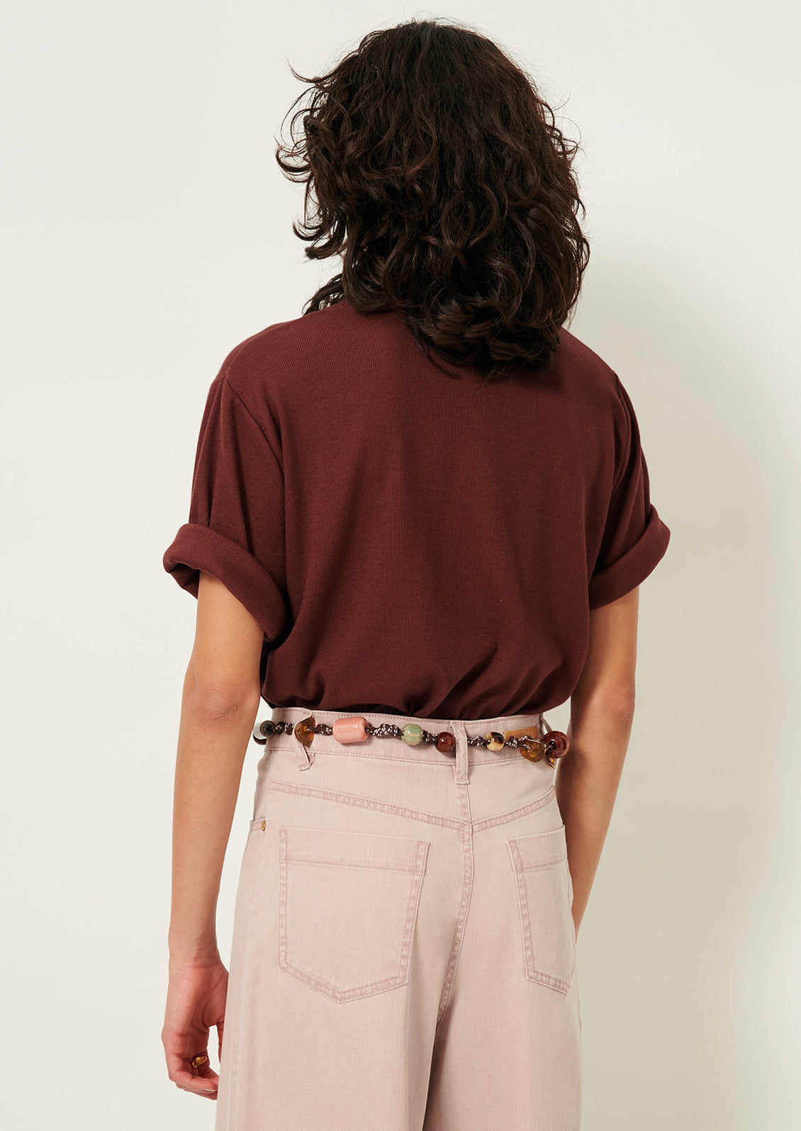 A woman wearing a short sleeve t-shirt with cuffs rolled up.