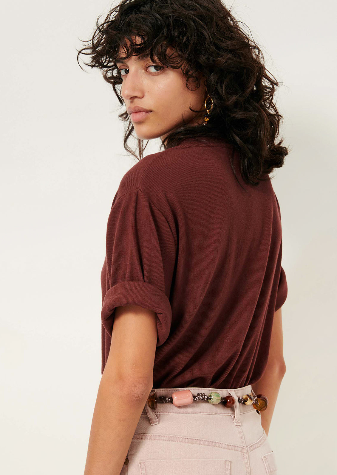 A woman wearing a short sleeve t-shirt with cuffs rolled up.