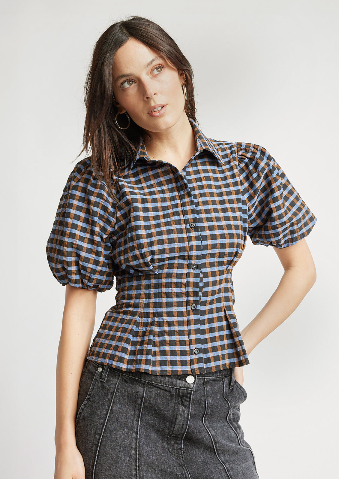 A woman wearing a puff short sleeve blouse with check print.
