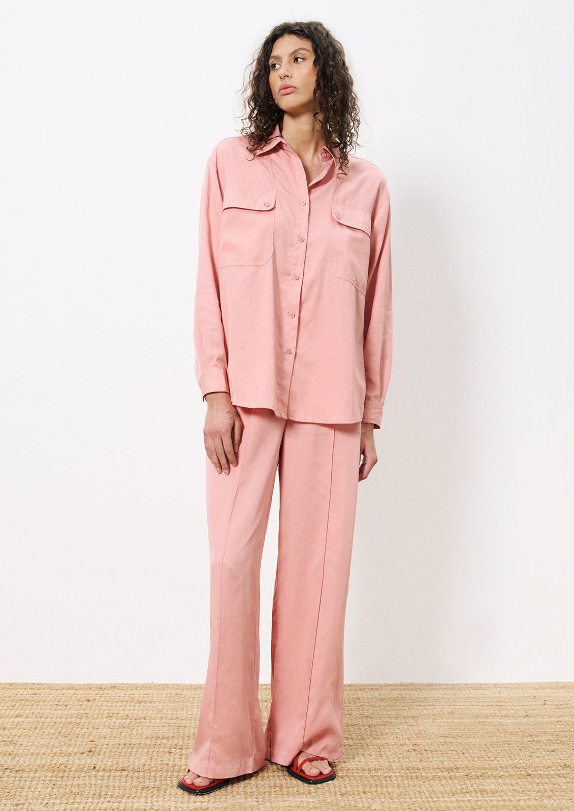 A woman wearing a pair of flowy pants in rose pink.