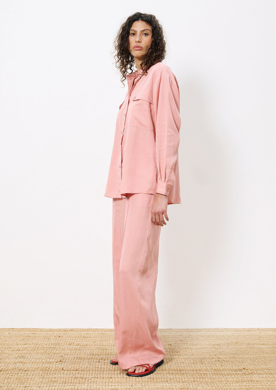 A woman wearing a pair of flowy pants in rose pink.