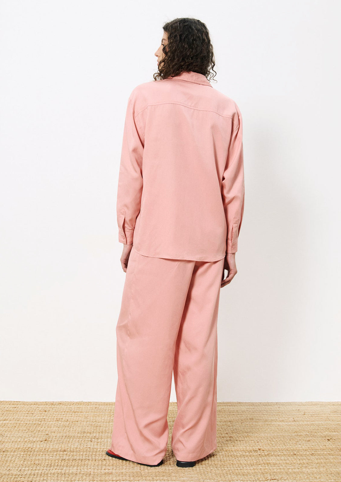 A woman wearing a pair of flowy pants in rose pink.