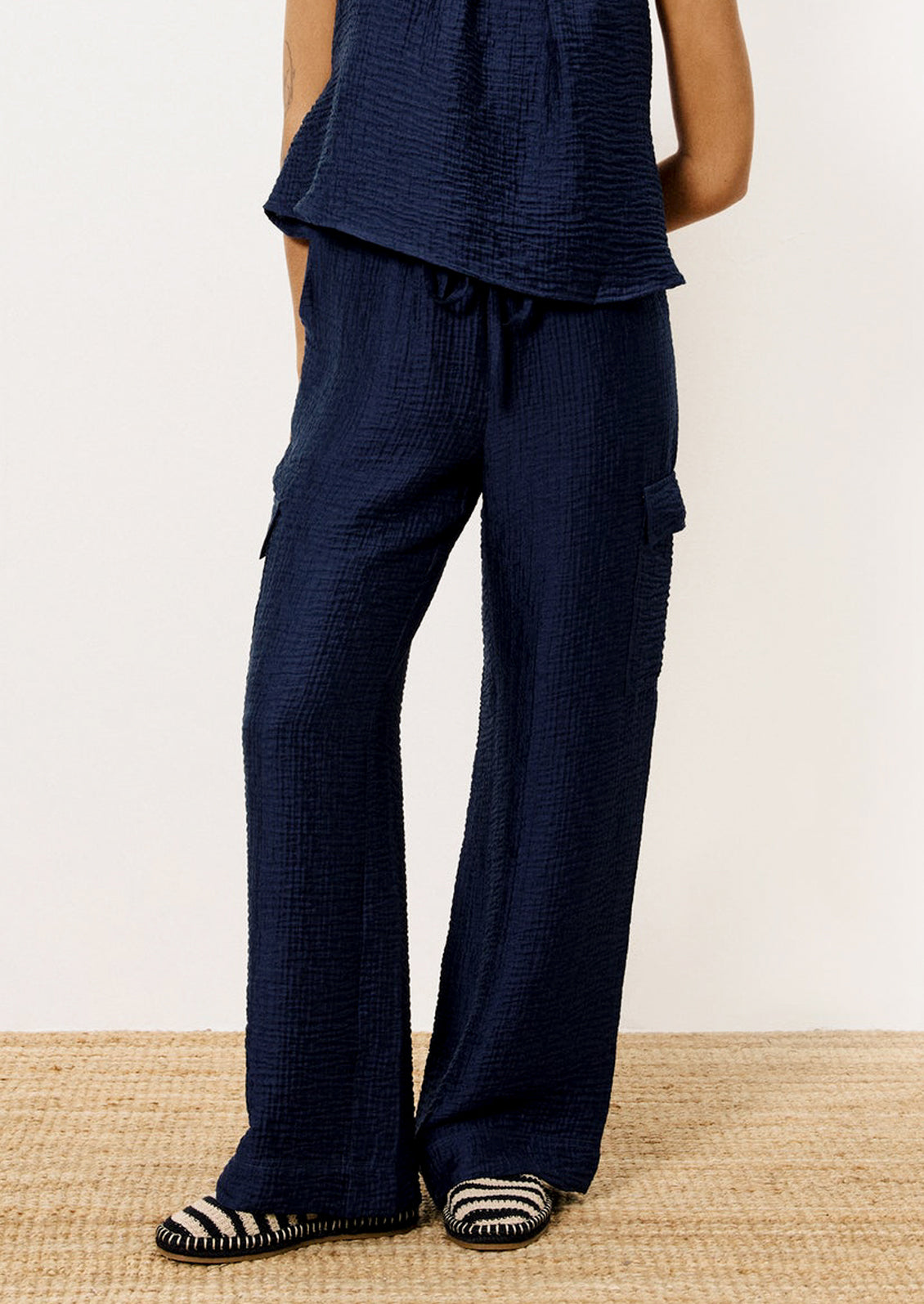 A person wearing a pair of navy blue crinkle texture cargo pants.