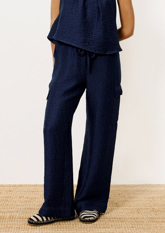 A person wearing a pair of navy blue crinkle texture cargo pants.