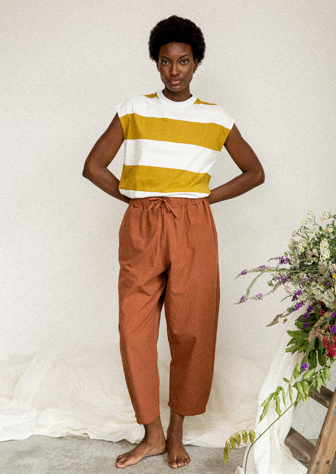 A woman wearing a white and mustard striped muscle tee.