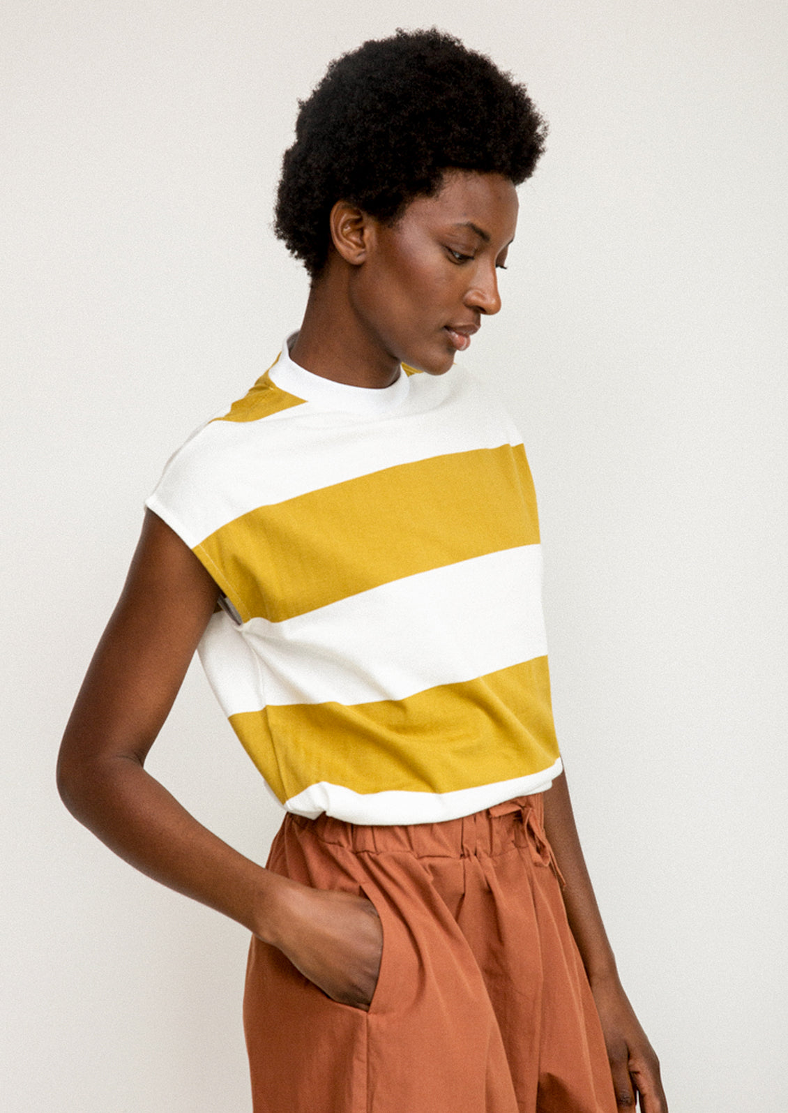 A woman wearing a white and mustard striped muscle tee.