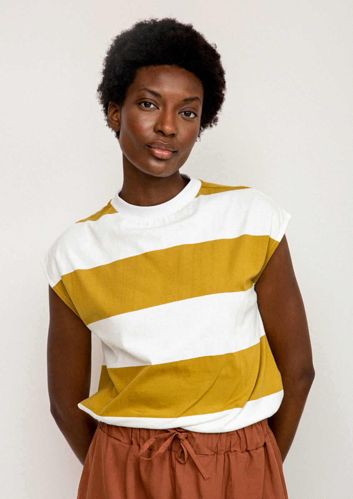 A woman wearing a white and mustard striped muscle tee.