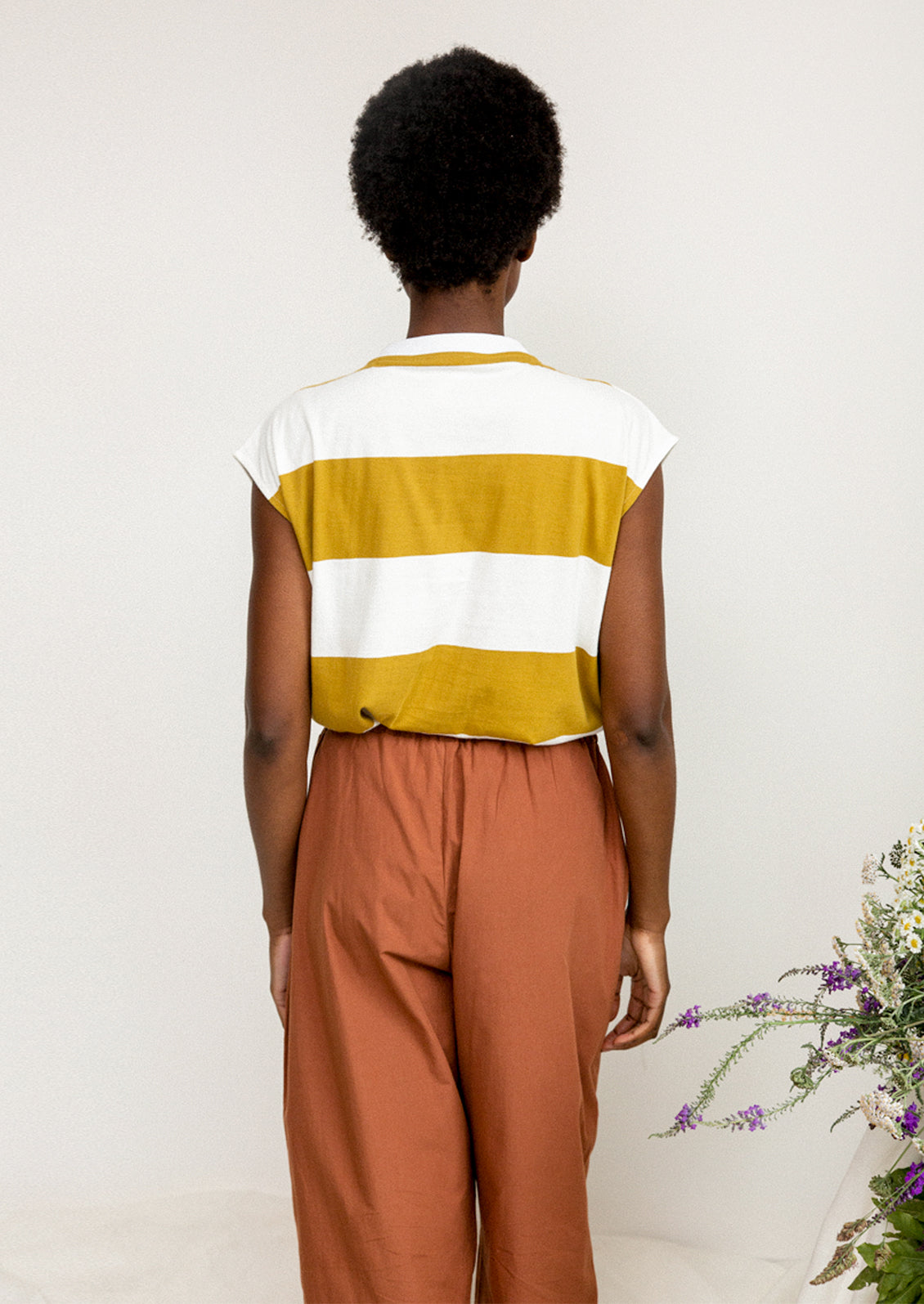 A woman wearing a white and mustard striped muscle tee.