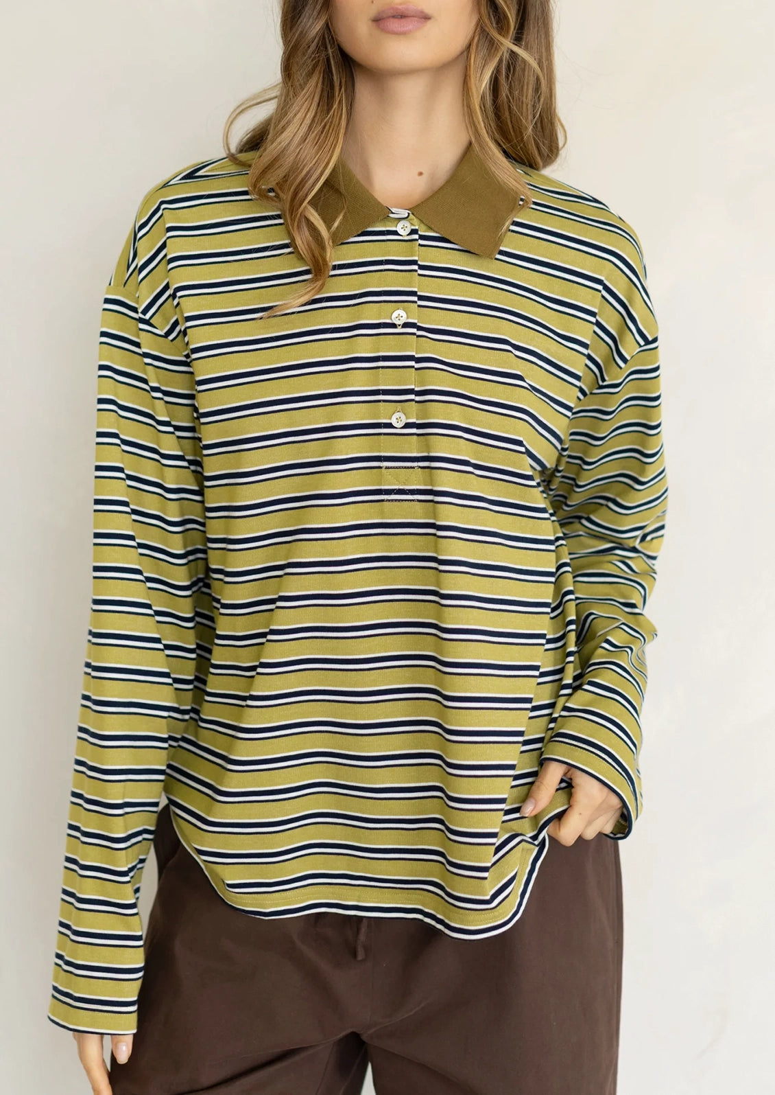 A woman wearing a long sleeve striped t-shirt with polo collar, chartreuse with white and black stripes.