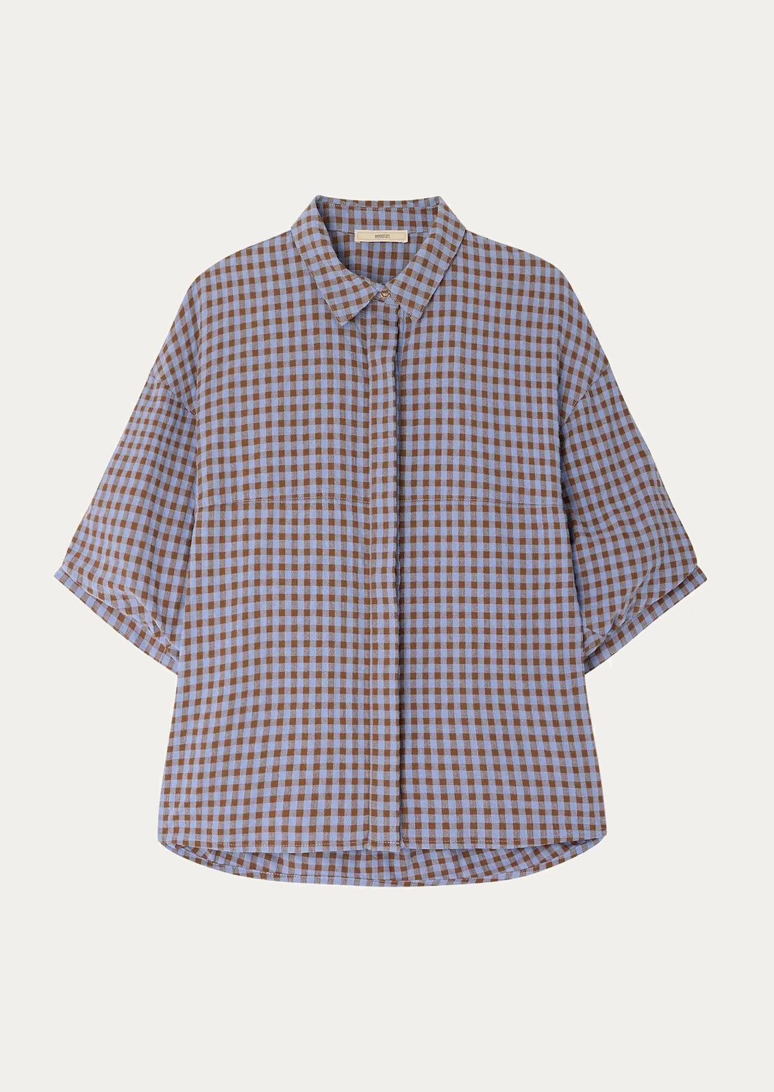 A woman wearing a puff sleeve blouse in brown and periwinkle checker.