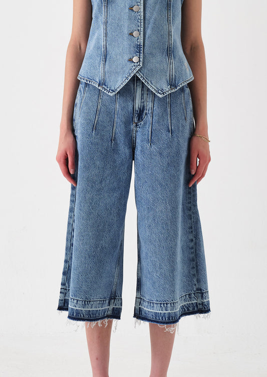 A person wearing a pair of denim culotte pants.