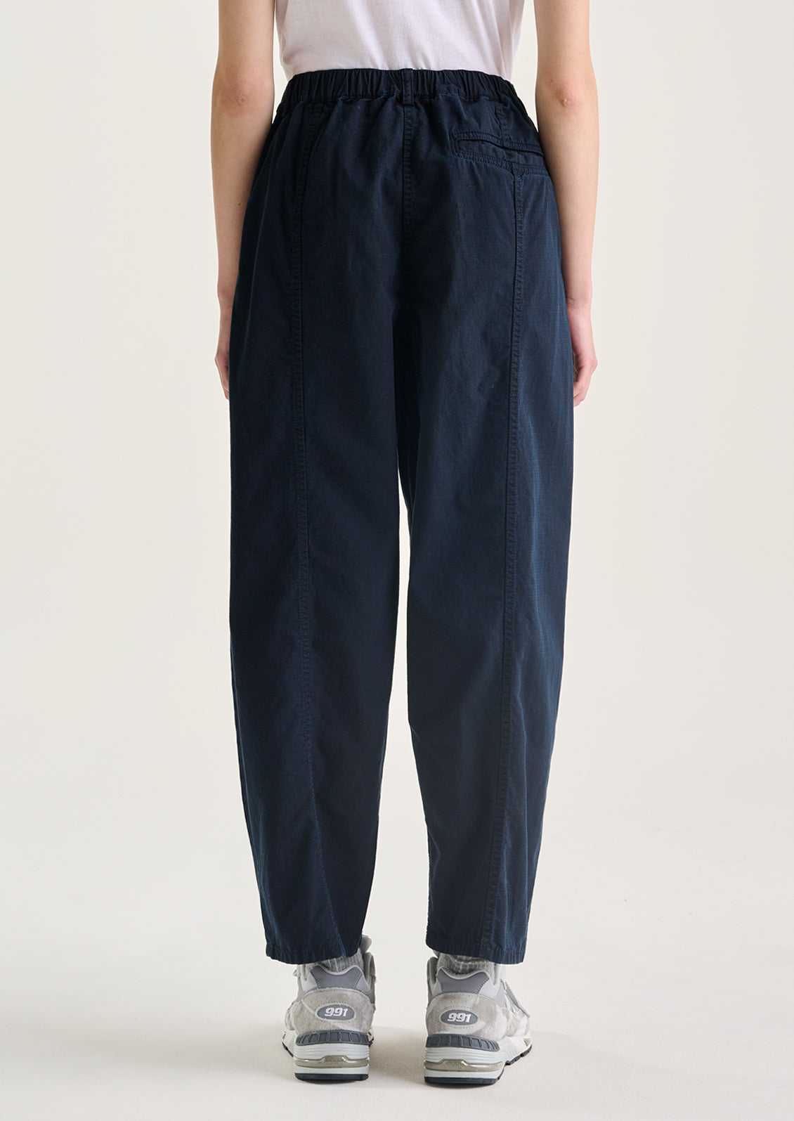 A woman wearing a pair of navy blue pants with tapered leg, in ripstop cotton fabric.