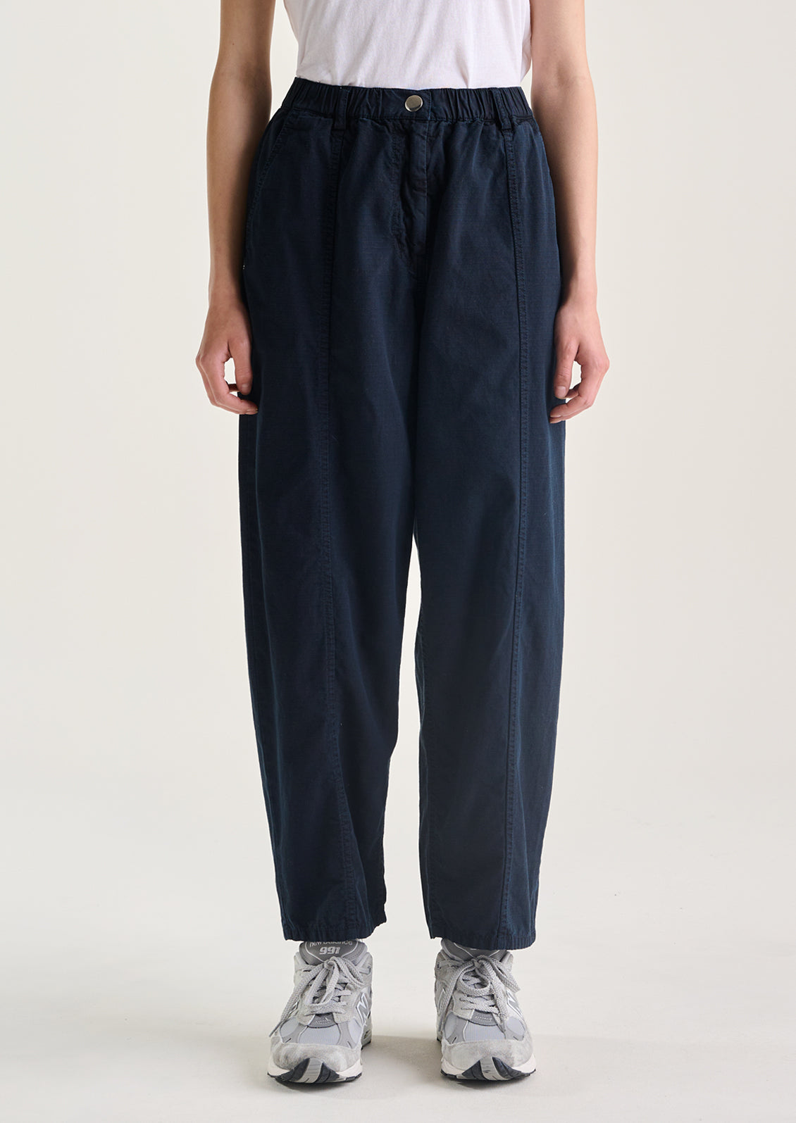 A woman wearing a pair of navy blue pants with tapered leg, in ripstop cotton fabric.