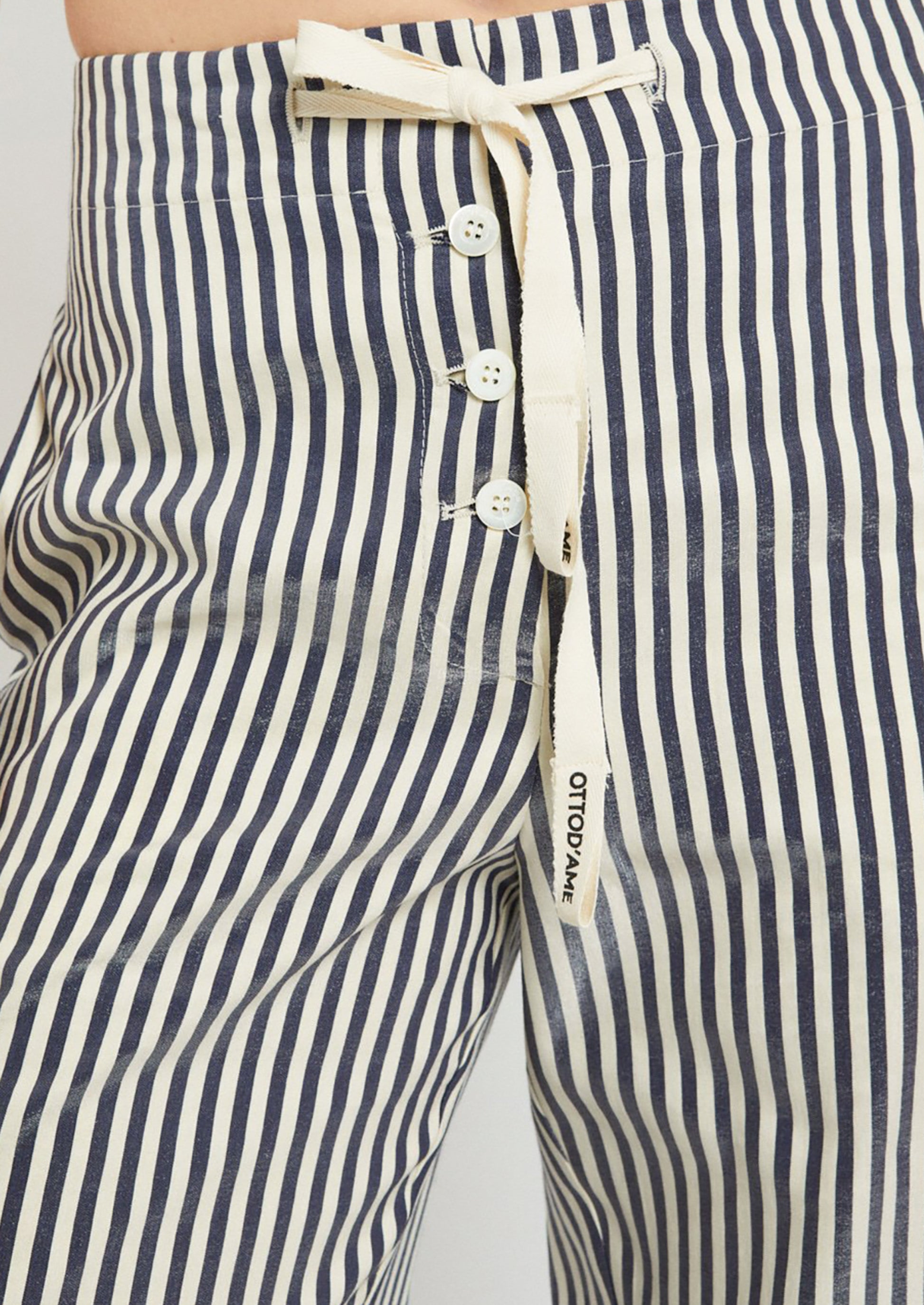 A pair of striped pants with exposed button fly.