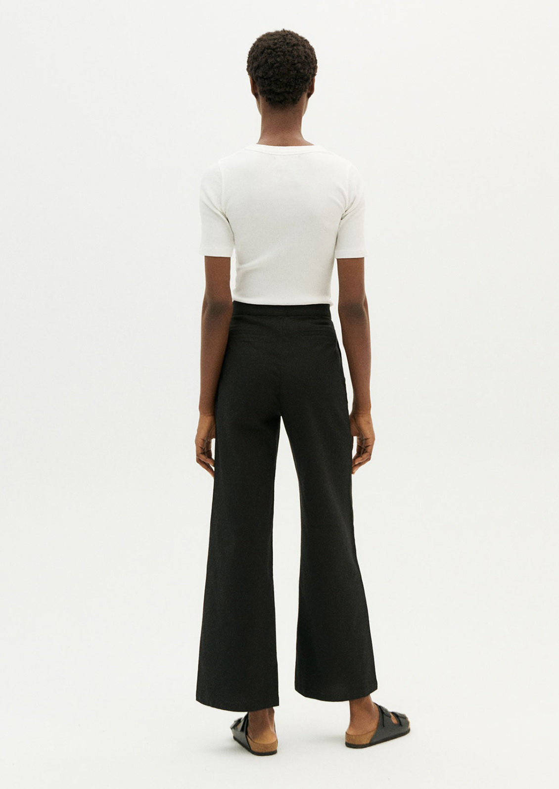 A person wearing a pair of ankle length cotton pants in black with slight wide leg.