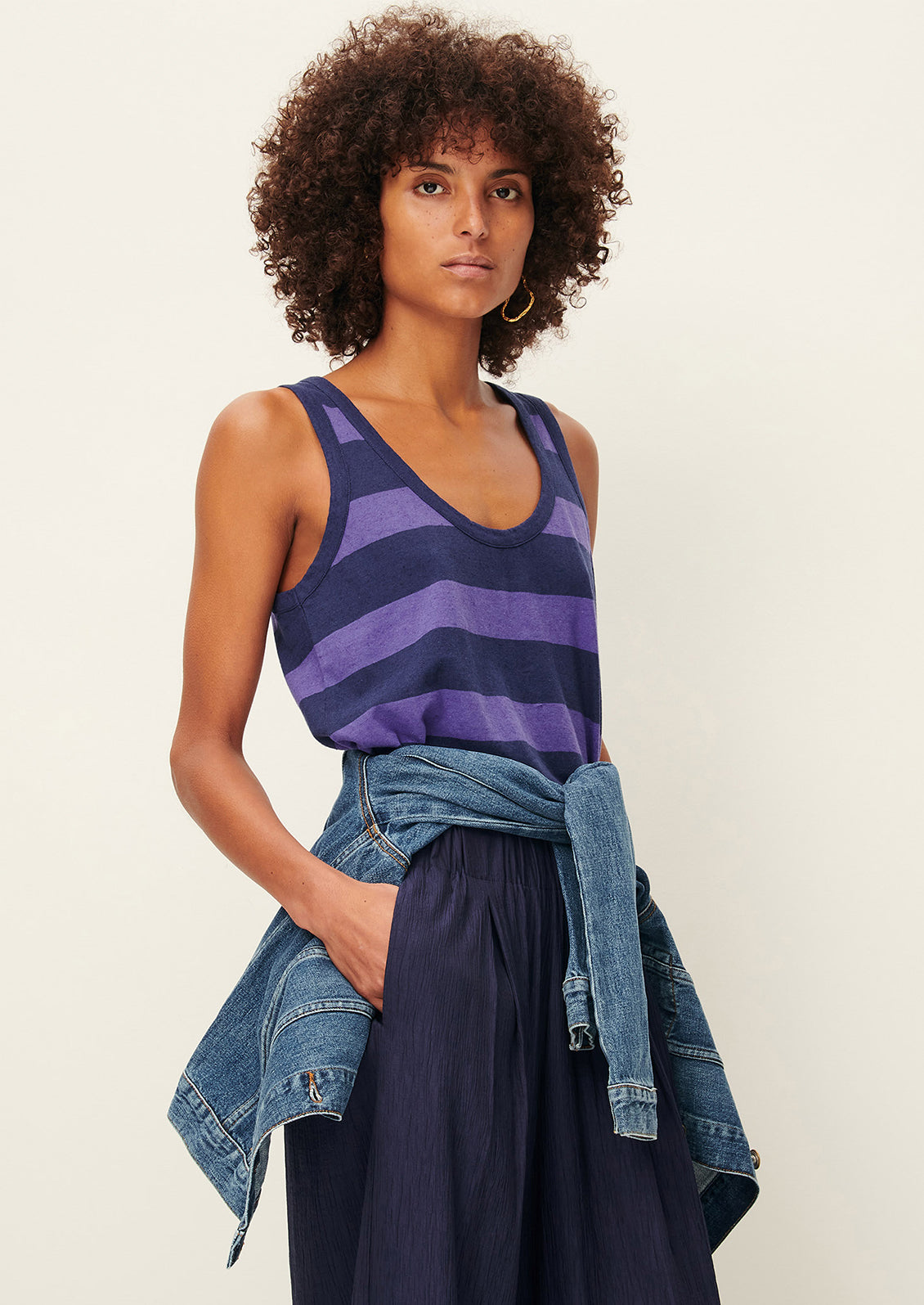 A woman wearing a scoop neck tank top in blue and purple stripes.