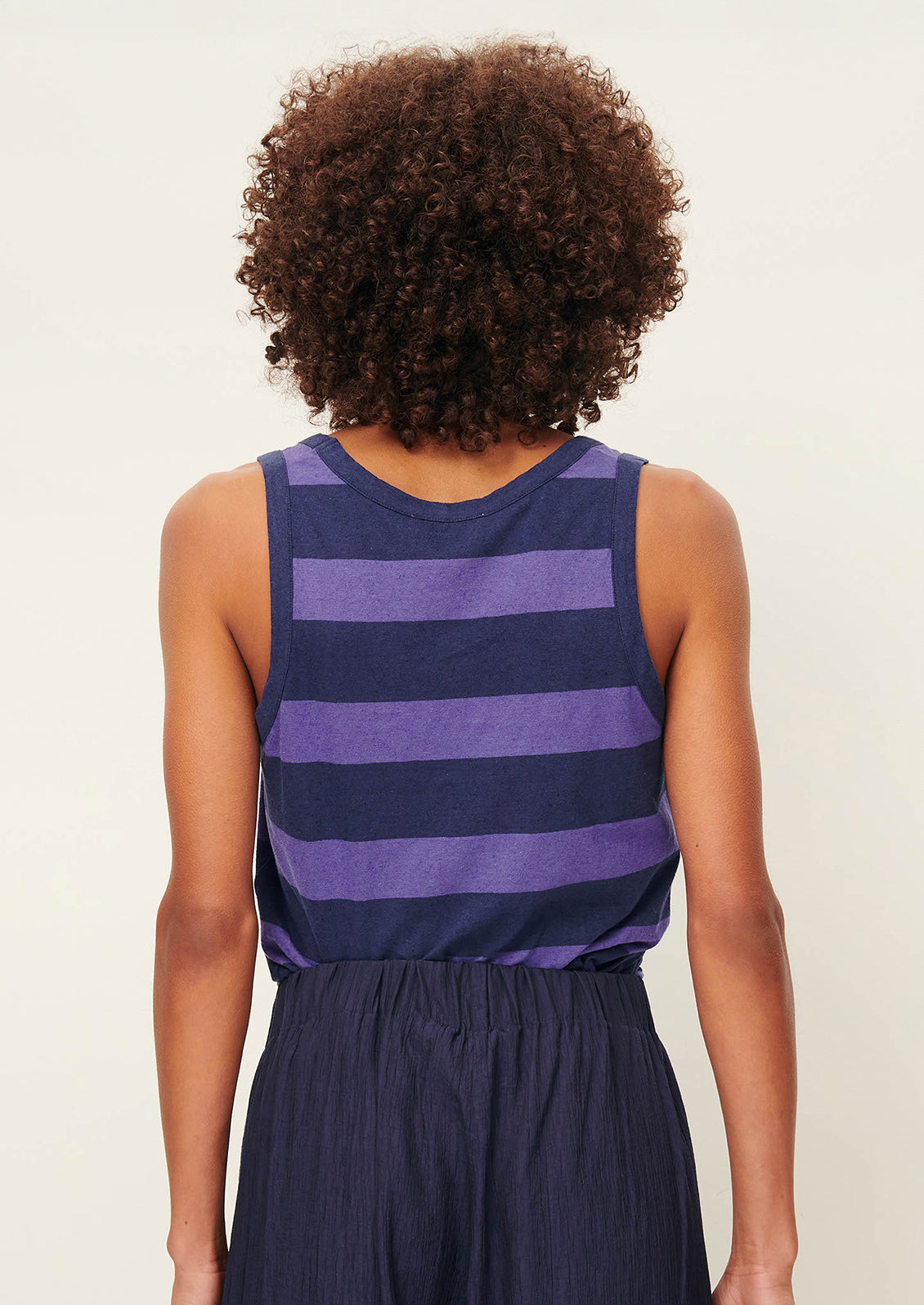 A woman wearing a scoop neck tank top in blue and purple stripes.