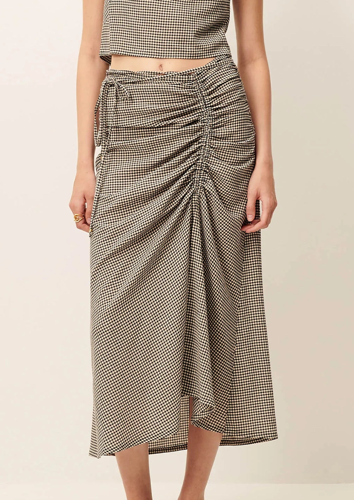 Person wearing a houndstooth patterned skirt on a beige background