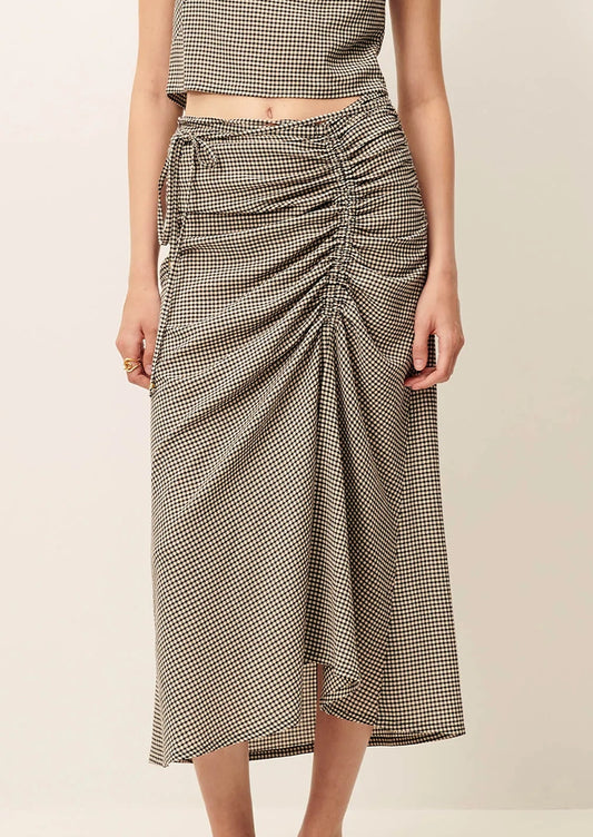 Person wearing a houndstooth patterned skirt on a beige background