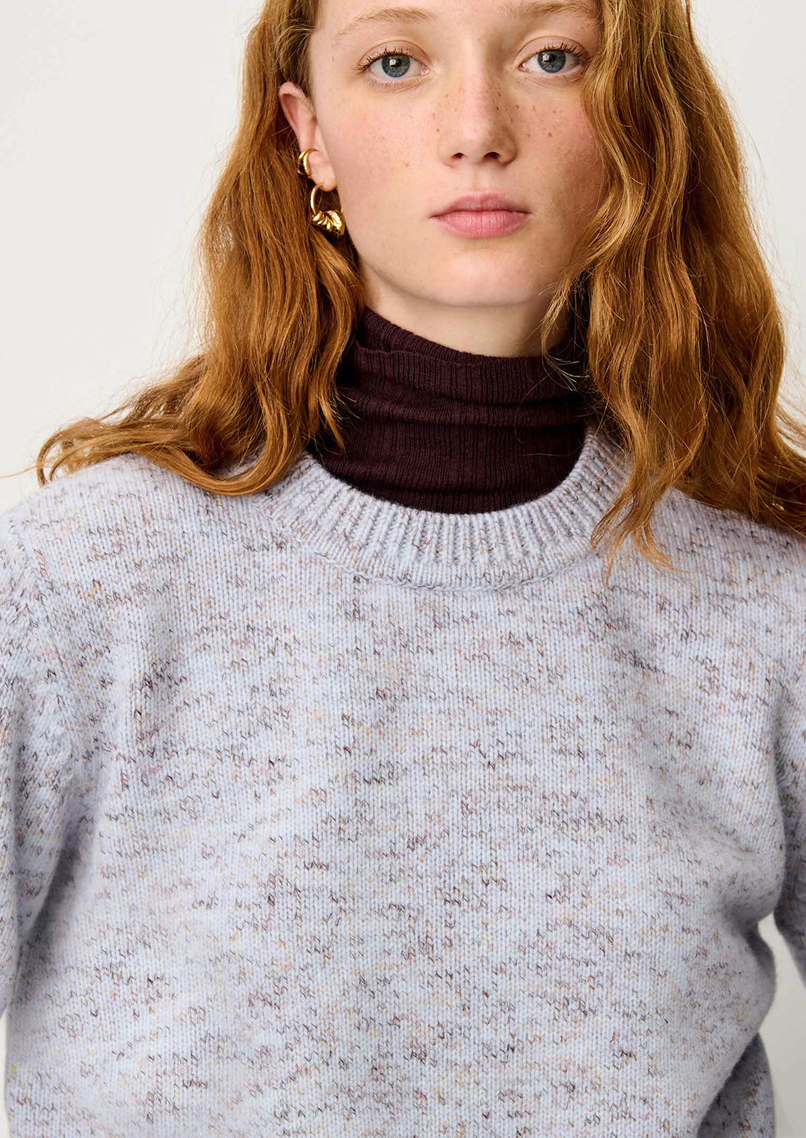 A woman wearing a wool sweater in periwinkle yarn mix.