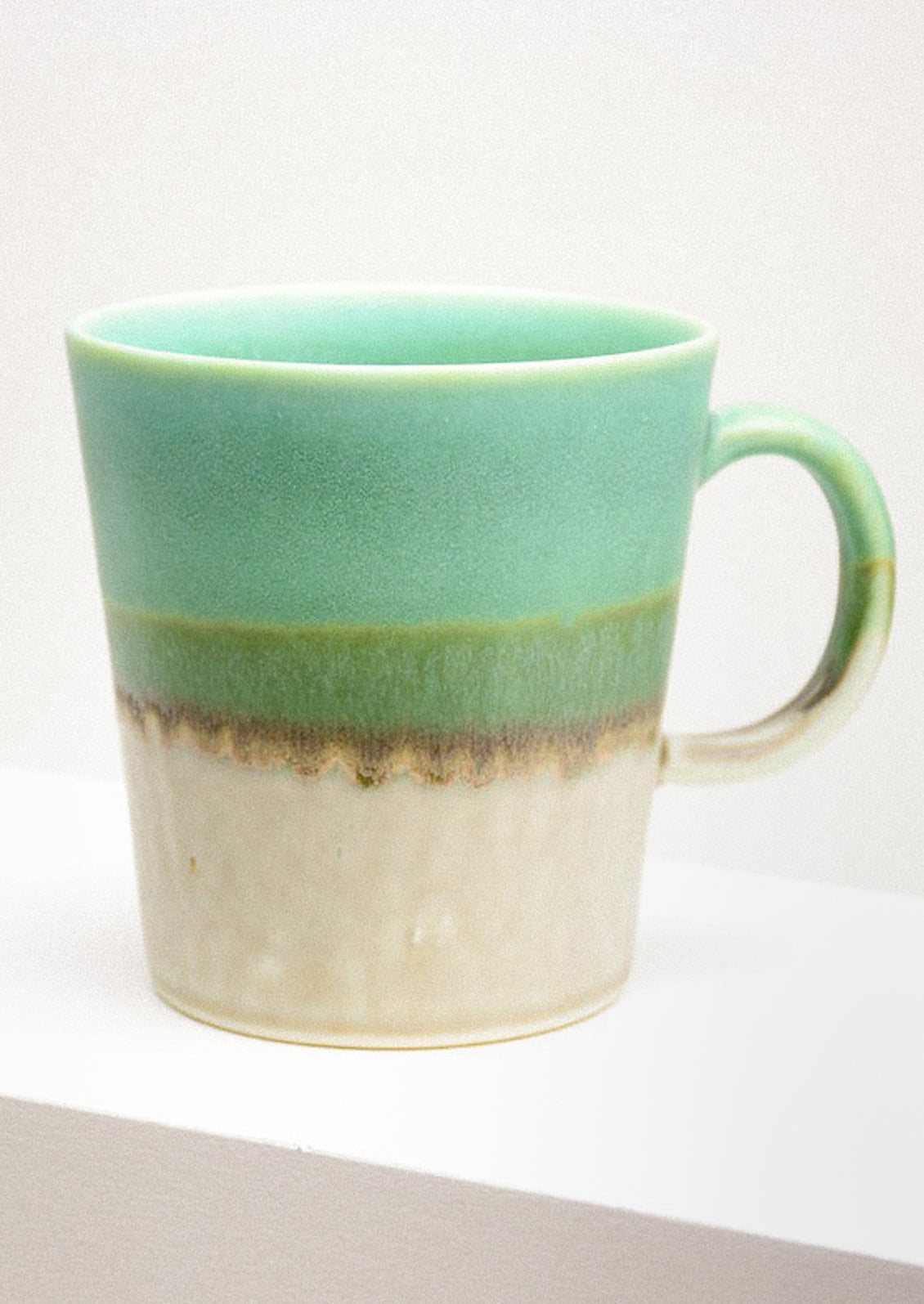 Green and beige ceramic mug on a white background