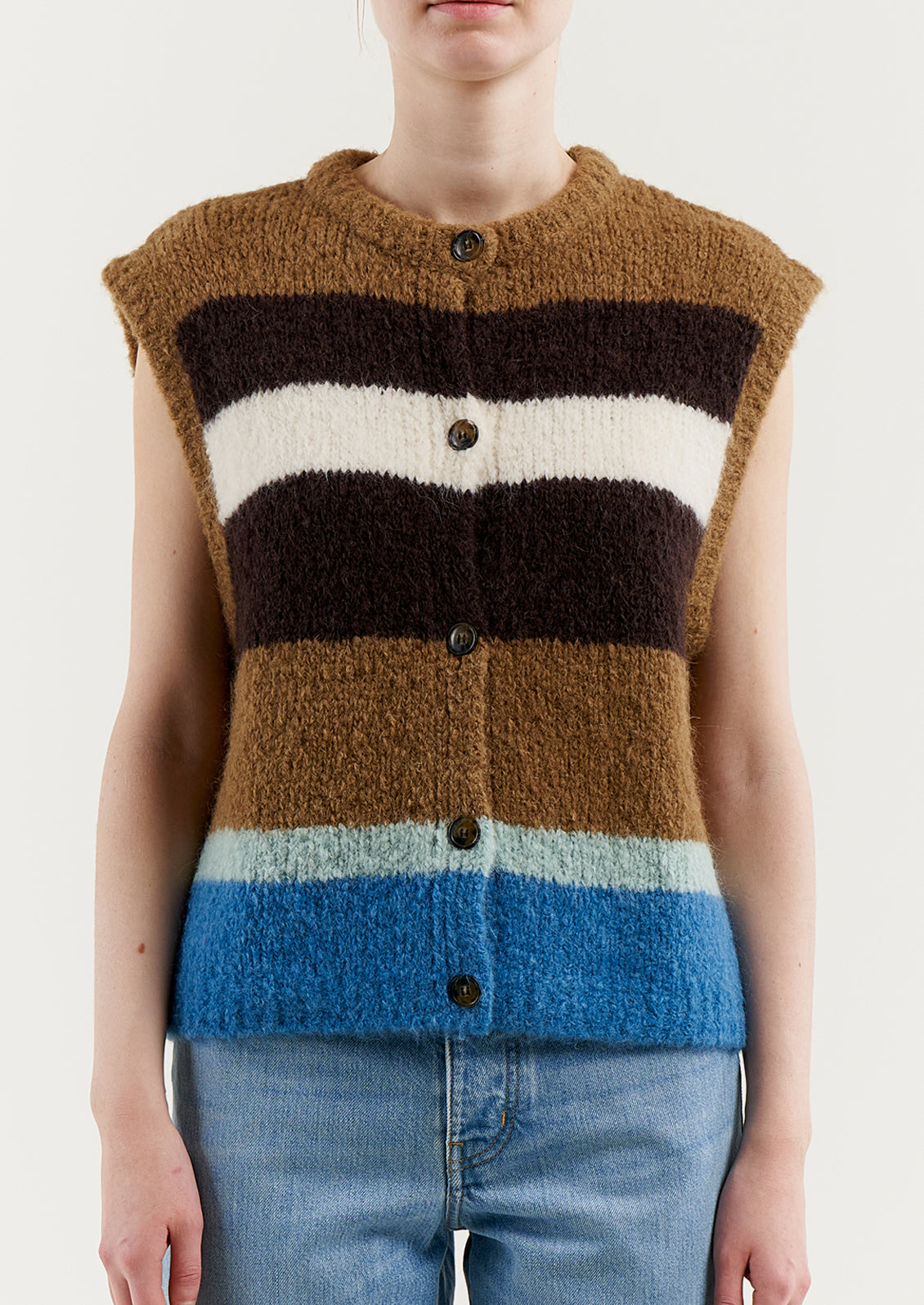 A woman wearing a sleeveless, button front sweater vest in brown and blue stripes.