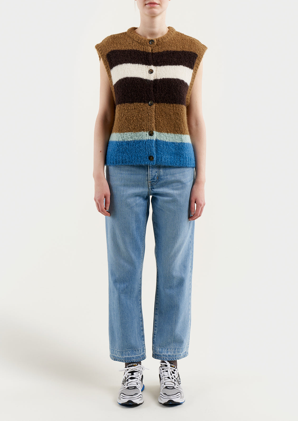 A woman wearing a sleeveless, button front sweater vest in brown and blue stripes.