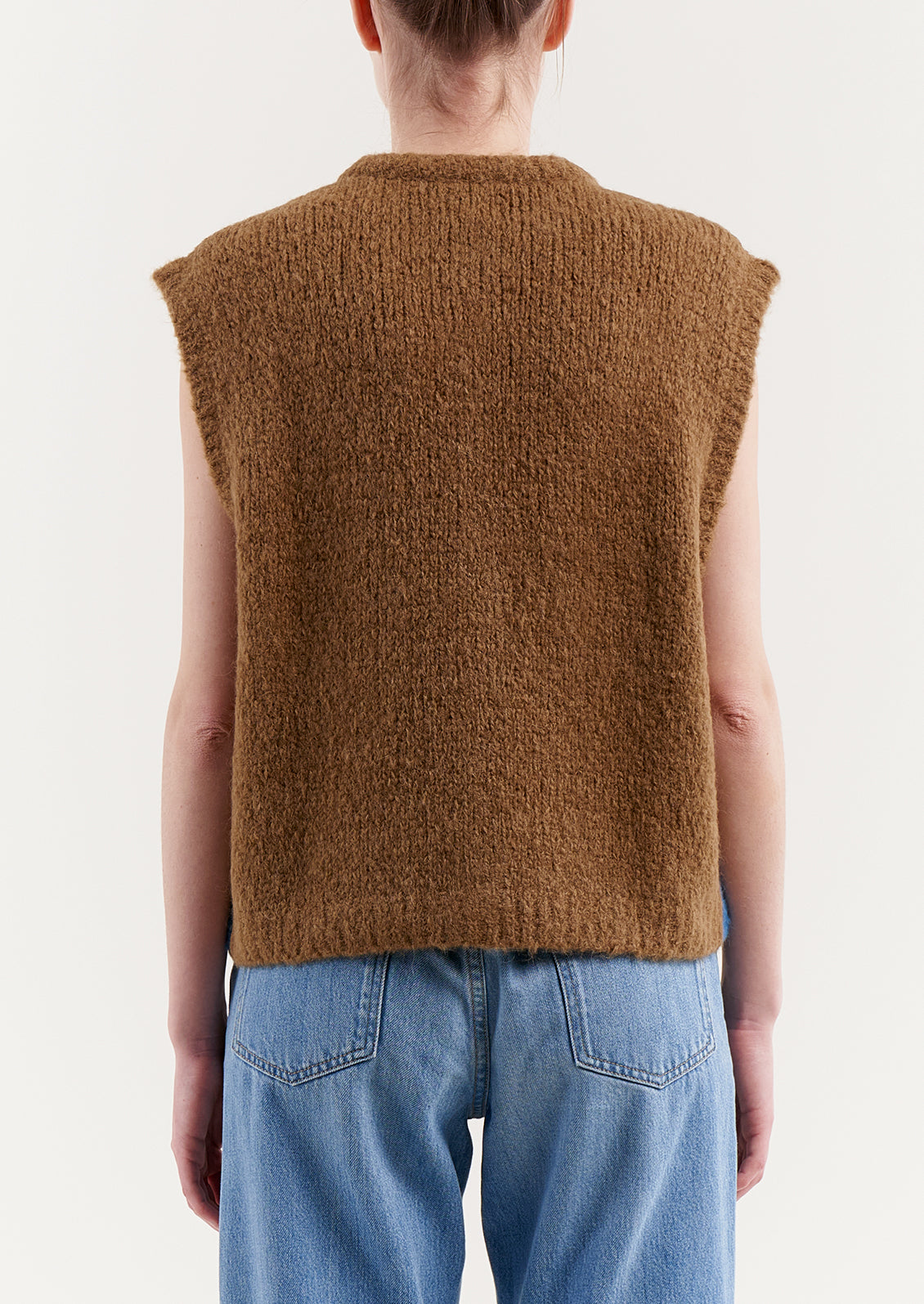 A woman wearing a sleeveless, button front sweater vest in brown and blue stripes.