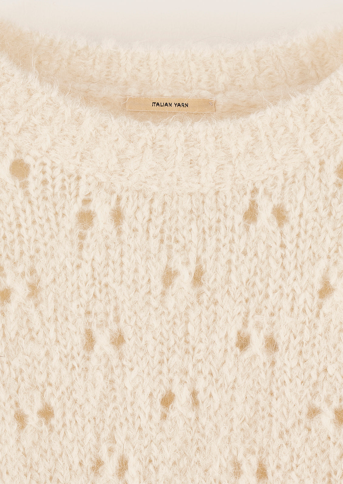 A fuzzy cream colored sweater with double birdseye cutout pattern throughout.