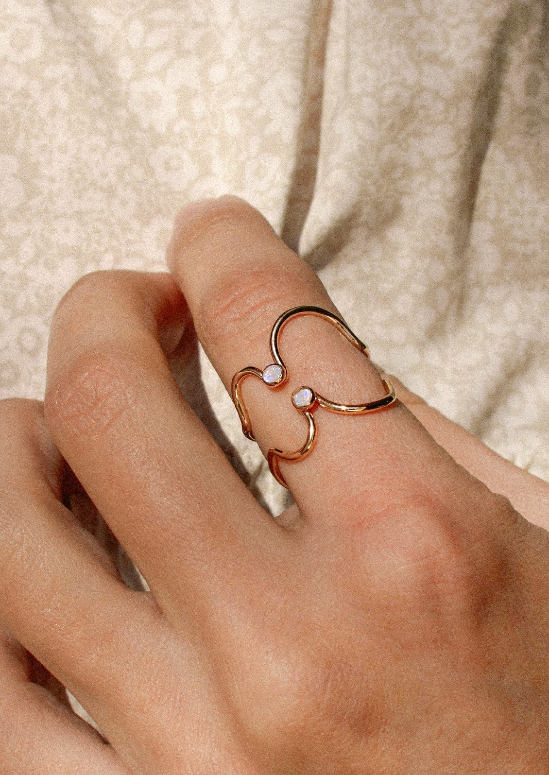 A woman wearing two gold rings with an Australian opal gem.