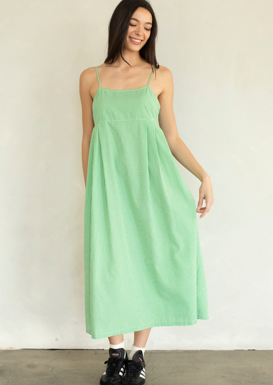A person wearing a calf-length dress in micro green gingham.