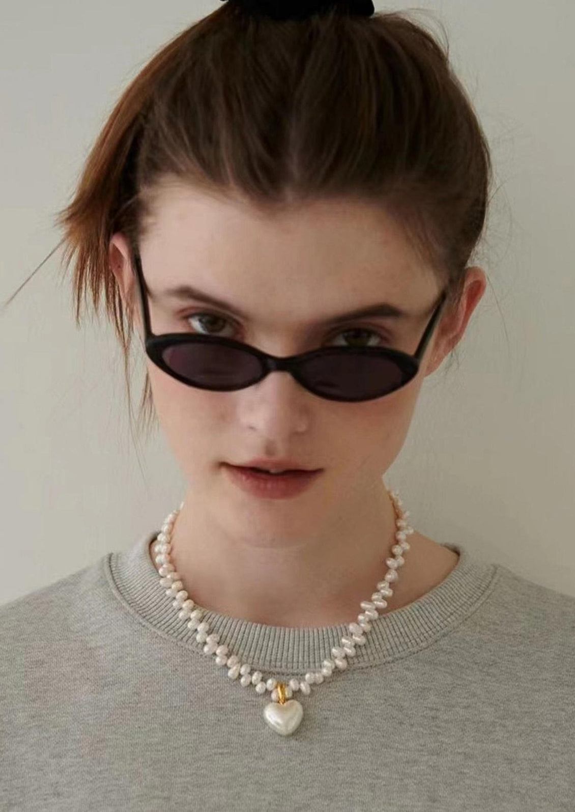 A white baroque pearl necklace with white pearlized heart shaped charm.