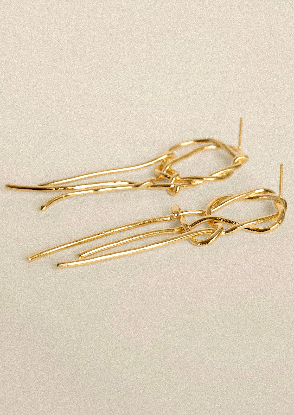 A pair of gold dangling intertwined earrings.