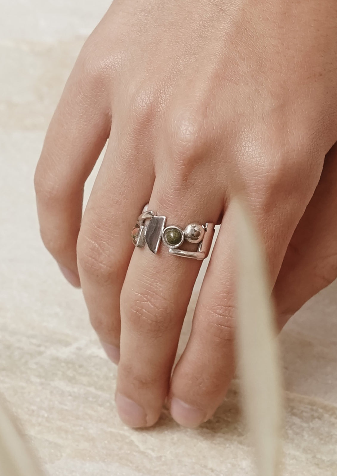 A silver ring with different geometric shapes among unakite gemstones.