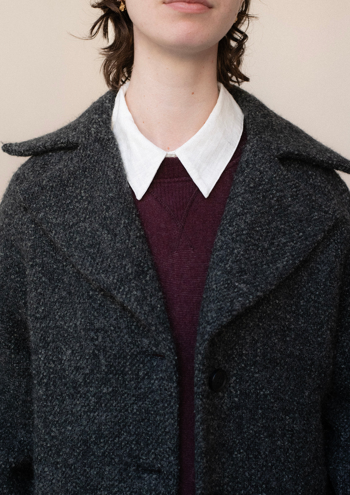 A woman wearing a long wool coat in dark grey speckled wool.