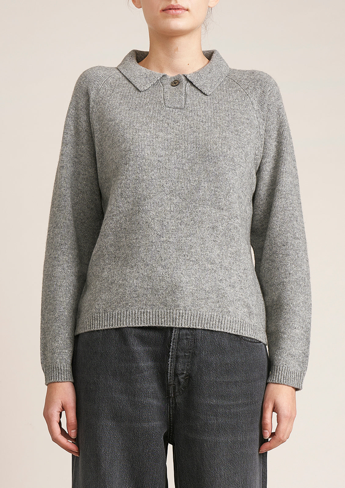 A woman wearing a heather grey long sleeve sweater with polo collar.