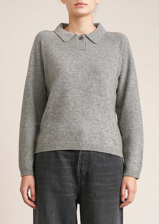 A woman wearing a heather grey long sleeve sweater with polo collar.