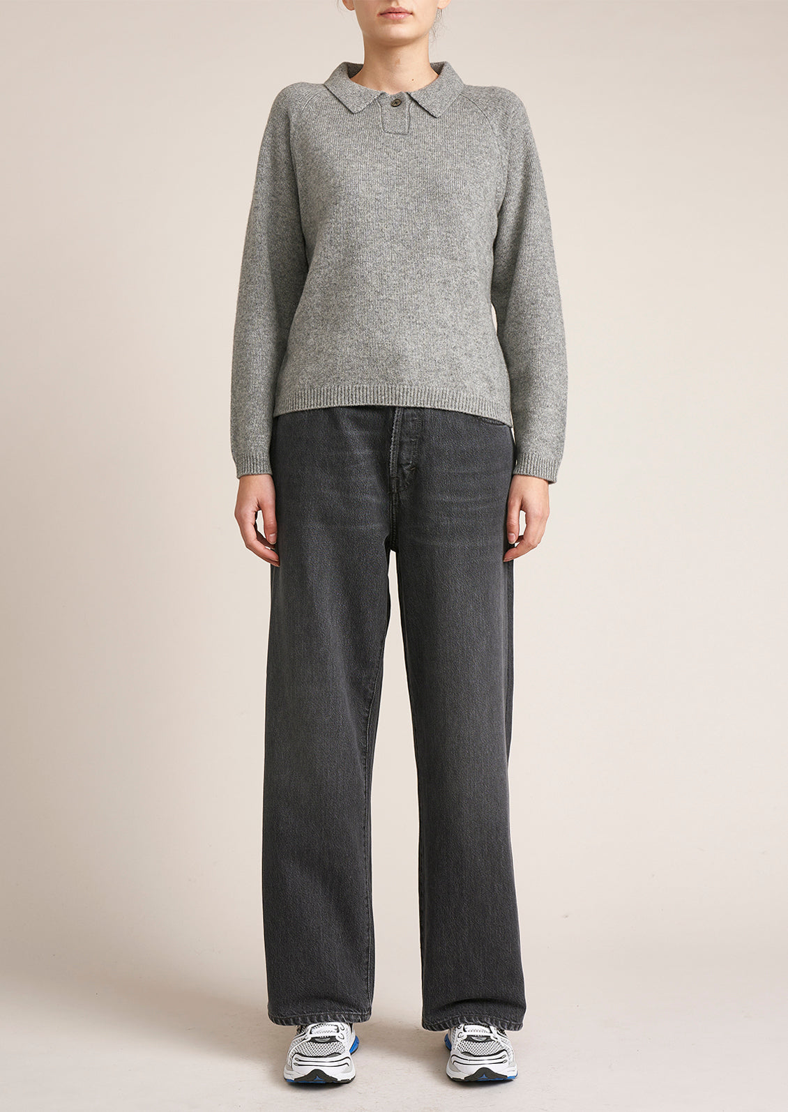 A woman wearing a heather grey long sleeve sweater with polo collar.