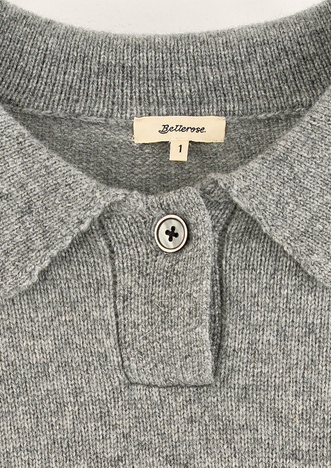 A heather grey long sleeve sweater with polo collar and single button detail.