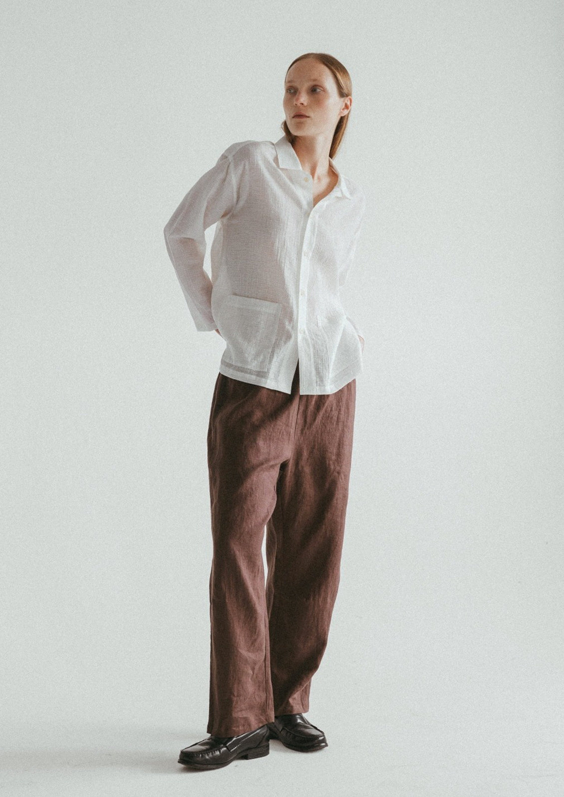 A woman wearing a semi-sheer, gauze-textured white button front shirt.