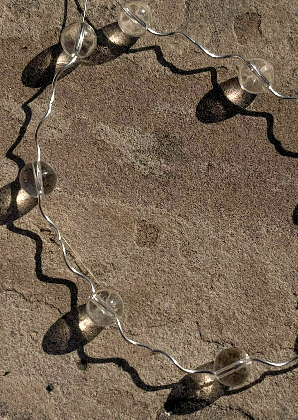 A necklace with a wavy sterling silver band adorned with clear round quartz.