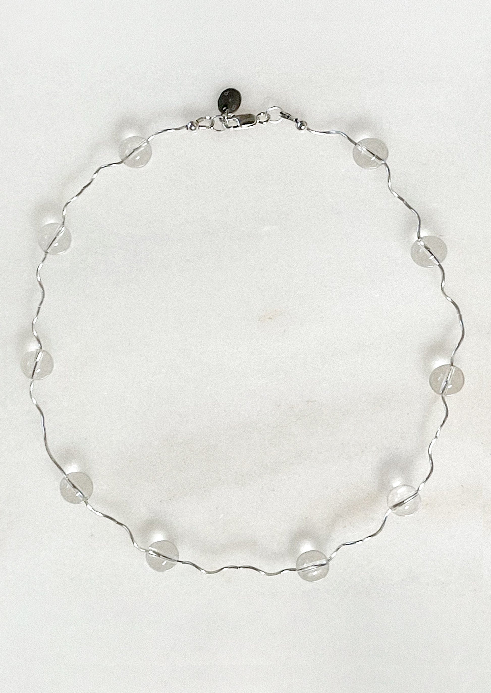 A necklace with a wavy sterling silver band adorned with clear round quartz stations.