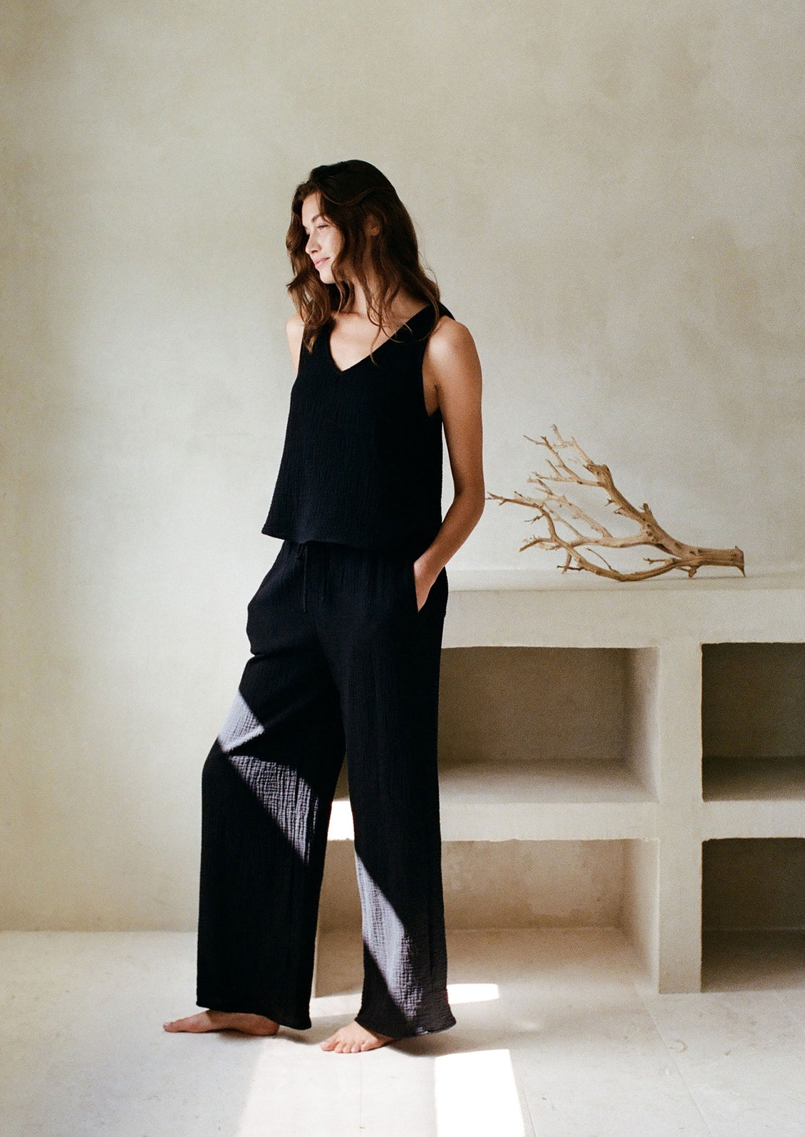 A woman in a black cotton tank top and matching pants. 