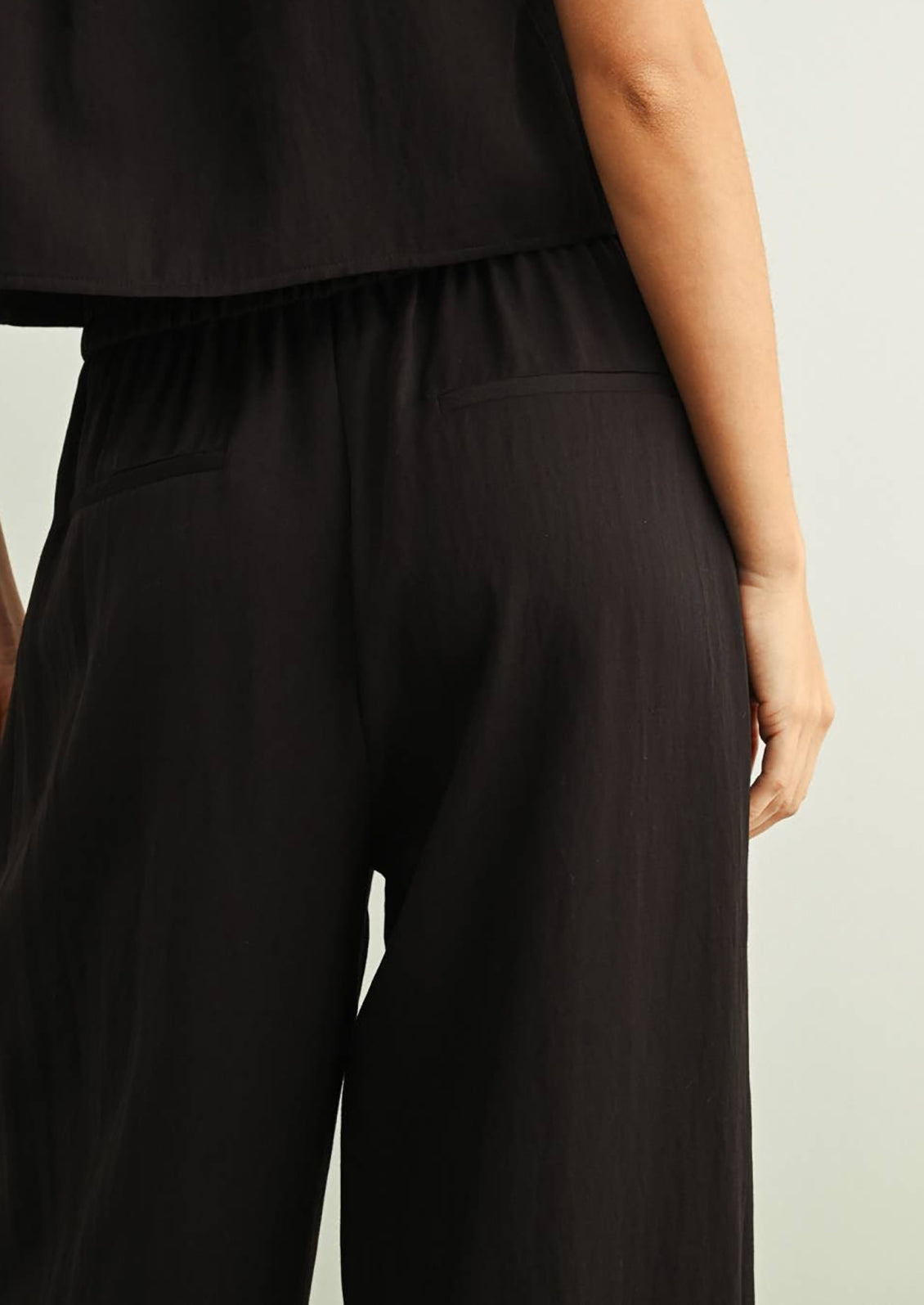 Person wearing black wide-leg pants against a neutral background