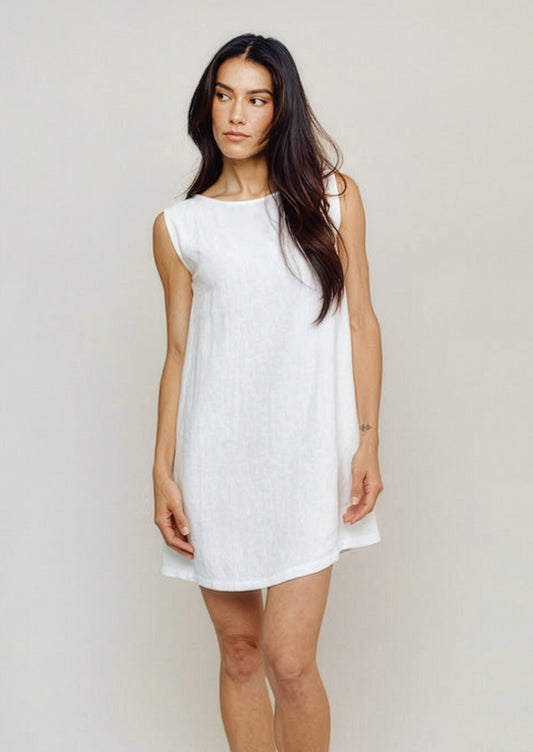 Woman wearing a white sleeveless dress against a plain background