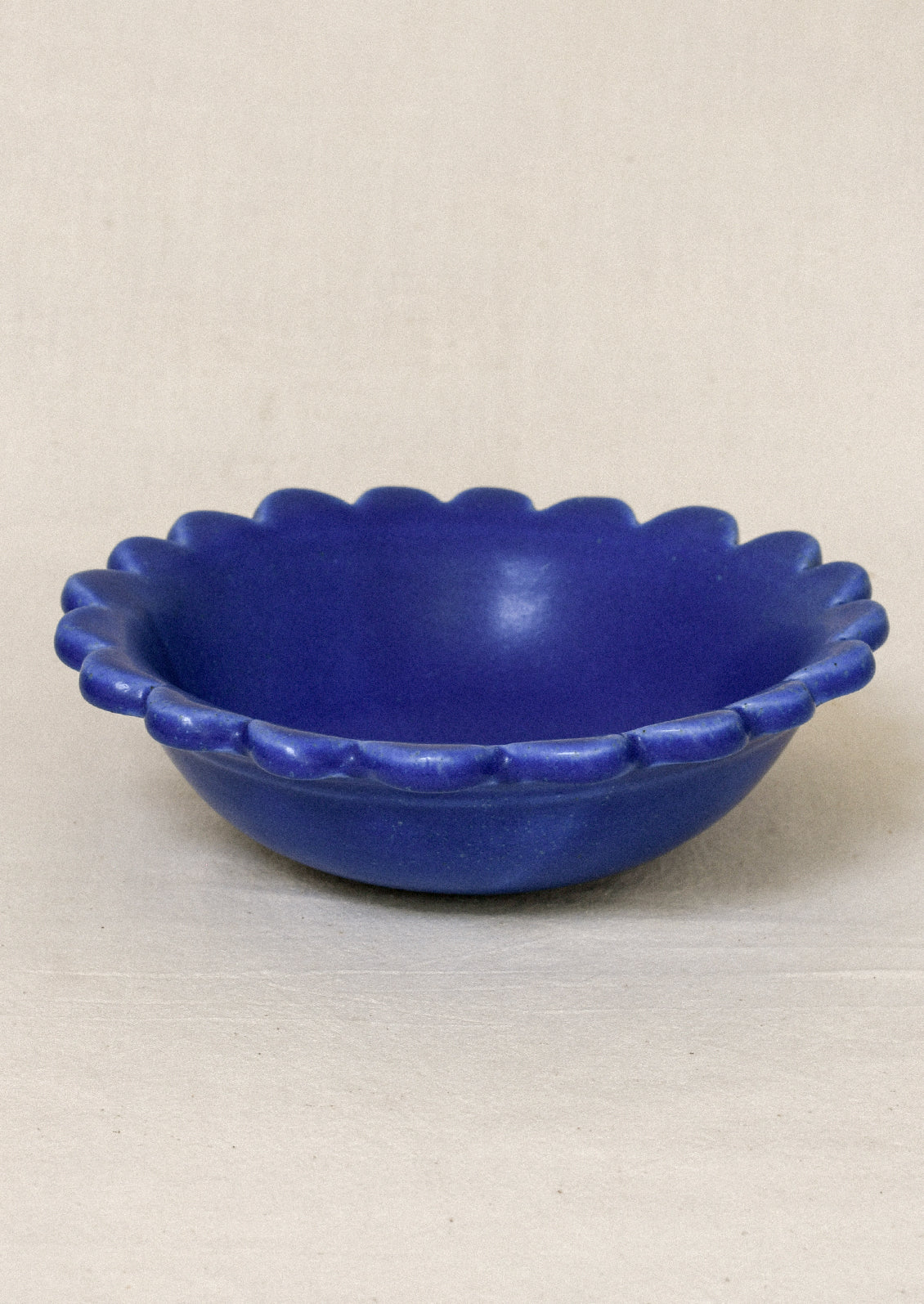 A ceramic scallop-edge bowl in a cobalt blue color.