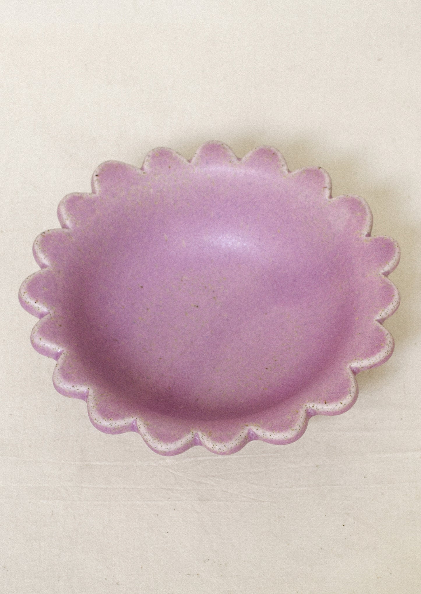 A ceramic scalloped edge bowl in a lilac color.