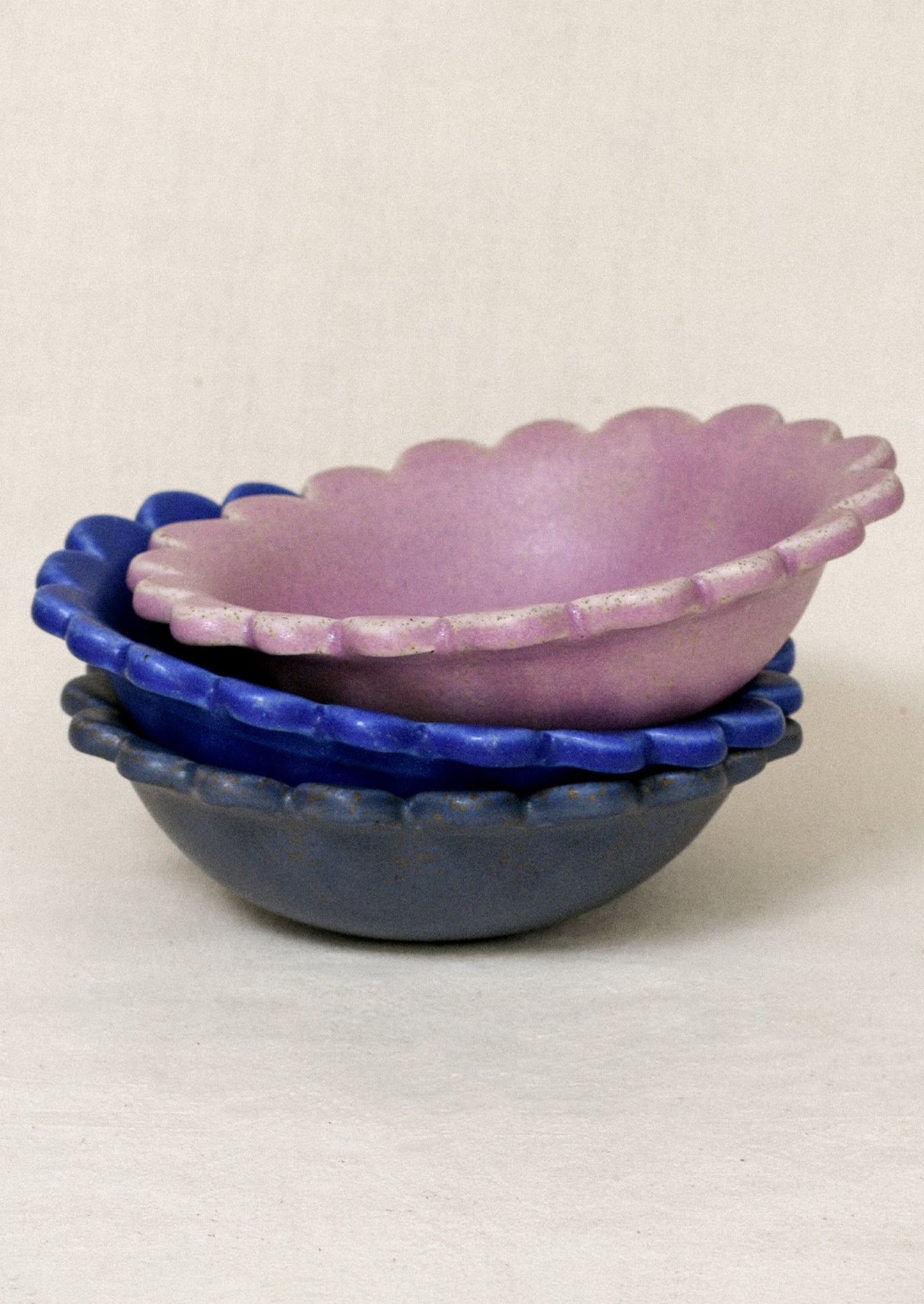 A stack of ceramic scallop-edge bowls in a variety of colors.