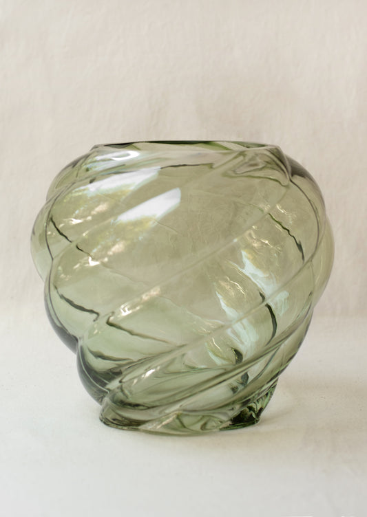 A glass vase in transparent olive green color, with twisted, tornado like texture.