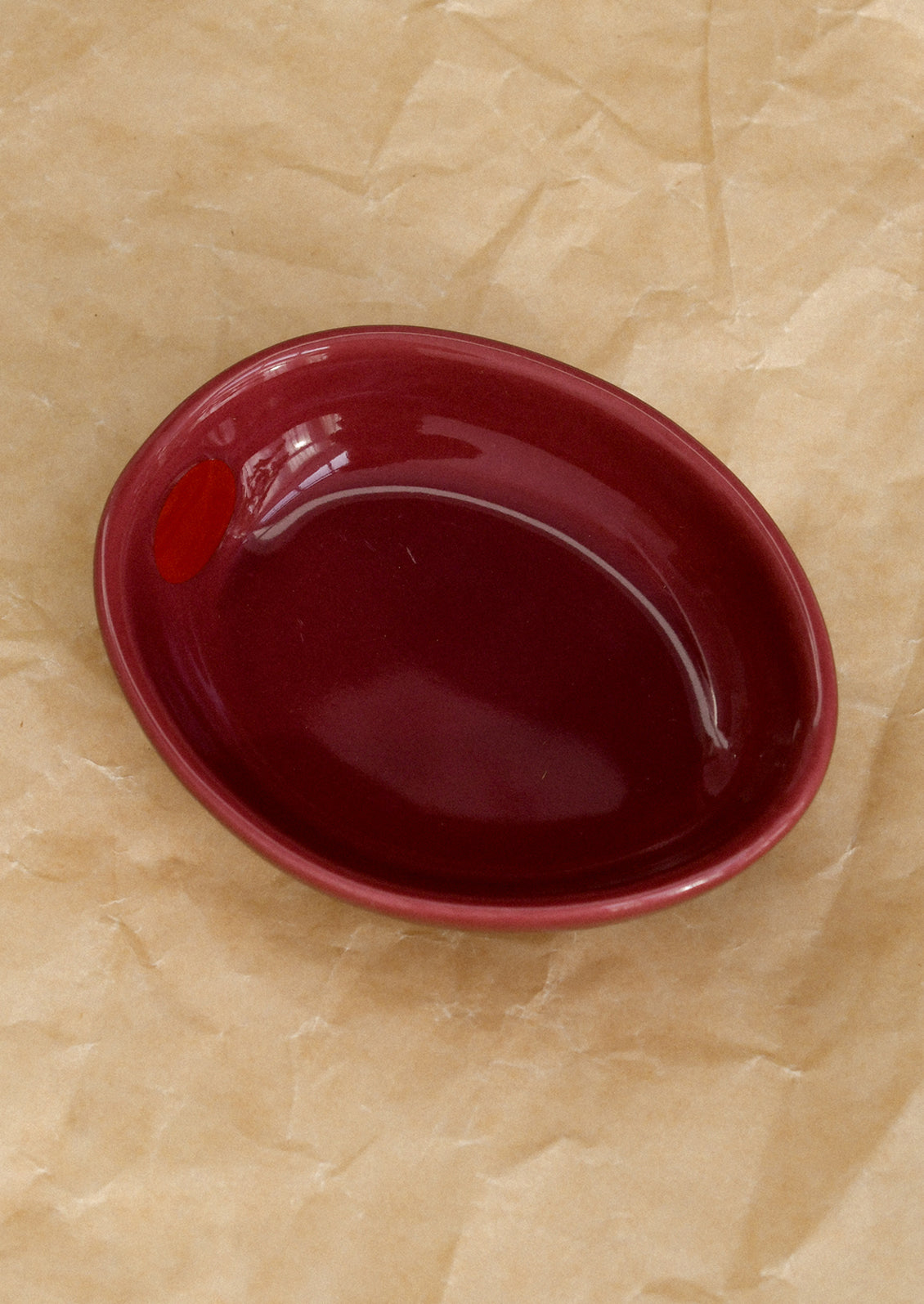 A small ceramic bowl shaped like an olive in berry red.